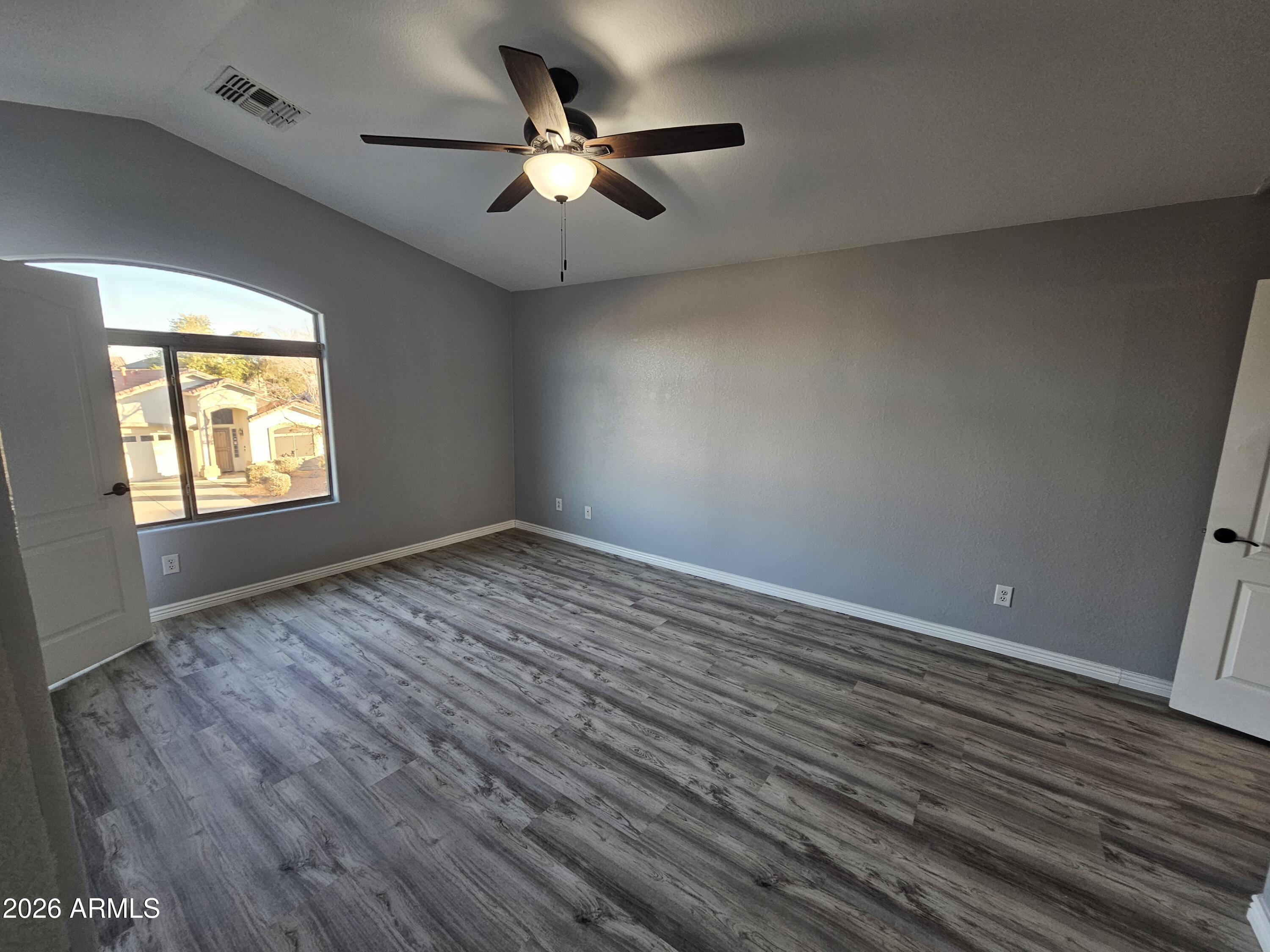 941 Mountain View Road San Tan Valley, AZ 85143 - Photo 30 of 48 an empty room with wooden floor chandelier fan and windows
