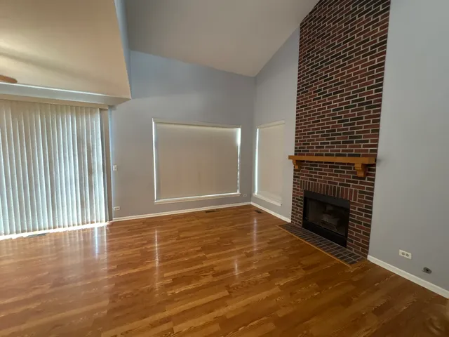 a view of an empty room with wooden floor and a fireplace