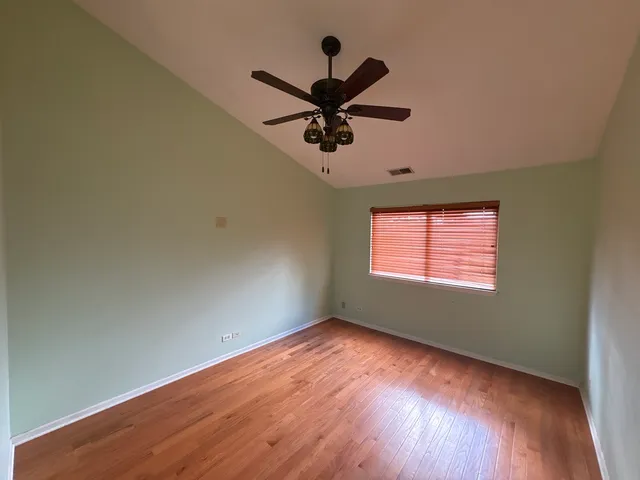 an empty room with wooden floor fan and windows