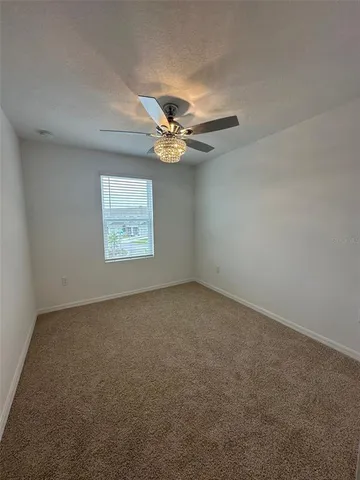 an empty room with windows and ceiling fan view