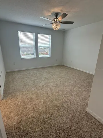 an empty room with windows and ceiling fan