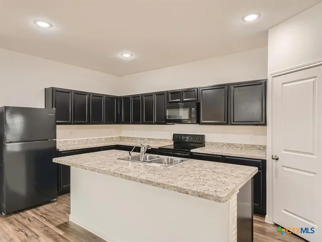 a kitchen with stainless steel appliances granite countertop a sink and a refrigerator
