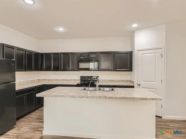 a kitchen with stainless steel appliances granite countertop a sink and a refrigerator