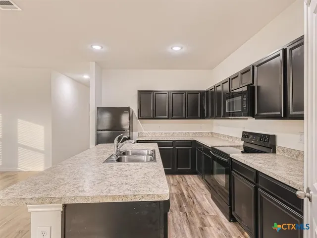 a kitchen with stainless steel appliances granite countertop a sink stove and cabinets