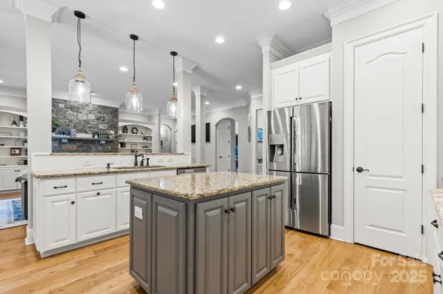 a kitchen with stainless steel appliances granite countertop a sink a refrigerator and a wooden floor