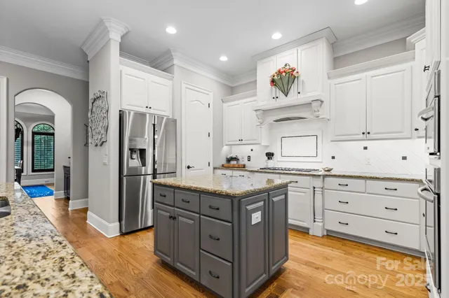 a kitchen with stainless steel appliances kitchen island granite countertop a refrigerator and a stove top oven