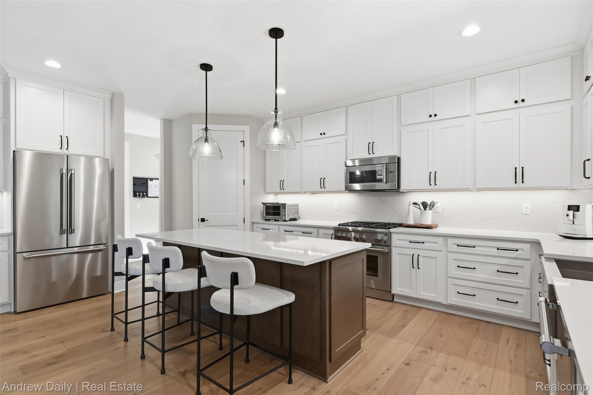 4661 Spears Road Pinckney, MI 48169 - Photo 21 of 56 Spacious kitchen featuring white shaker-style cabinetry, a dark wood-finish island, stainless steel appliances, light wood-finish flooring, and pendant lighting