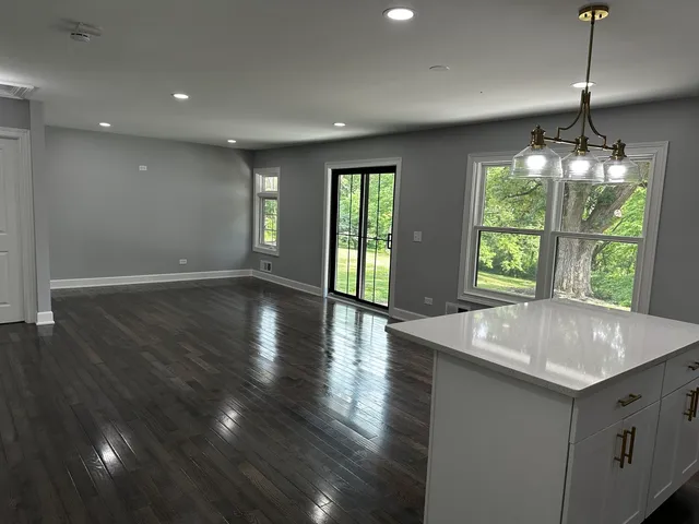 a kitchen with a sink chandelier and wooden floor