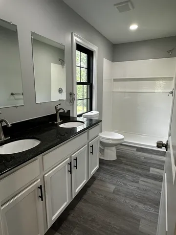 a bathroom with a granite countertop sink a toilet a mirror and a window