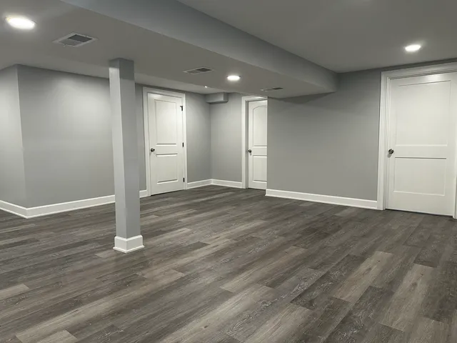 an empty room with wooden floor & windows
