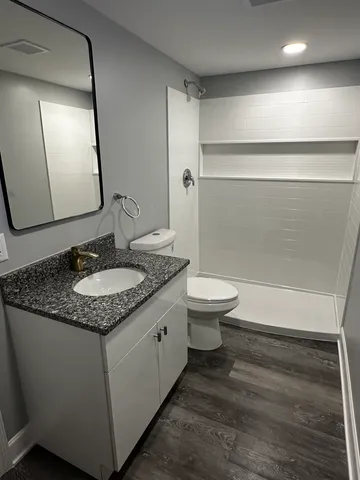a bathroom with a granite countertop sink toilet and shower
