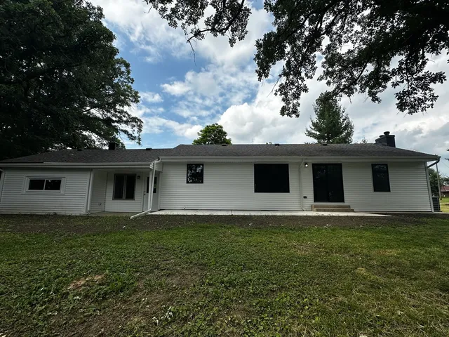 a house that has a big yard large trees with wooden fence