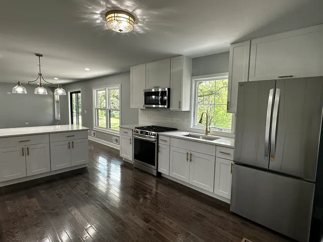 a kitchen with a refrigerator a sink dishwasher a stove and a window