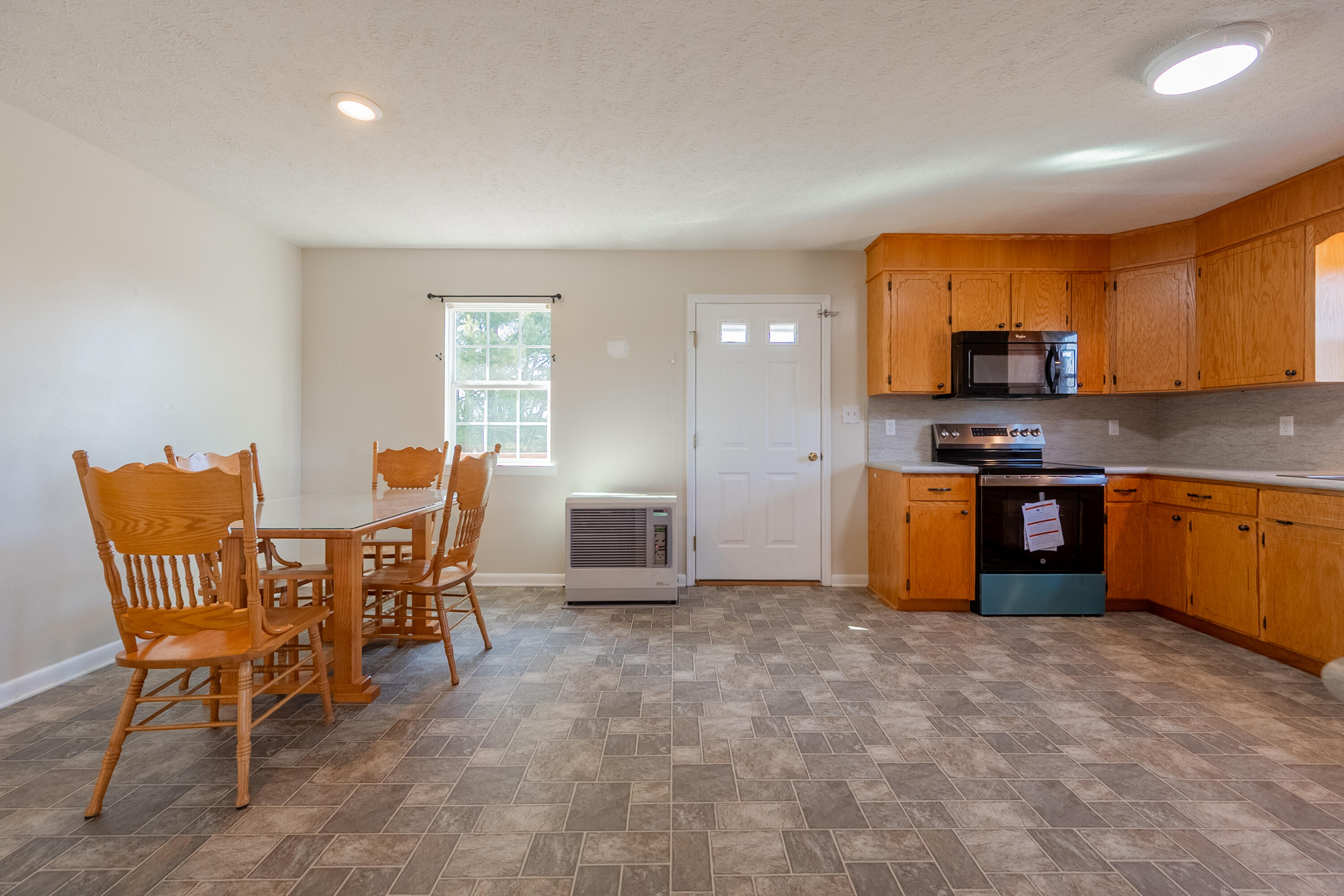 2448 Kyle Weeks Road Southwest Willis, VA 24380 - Photo 15 of 65 a kitchen with stainless steel appliances granite countertop a stove top oven a sink a dining table and chairs with wooden floor