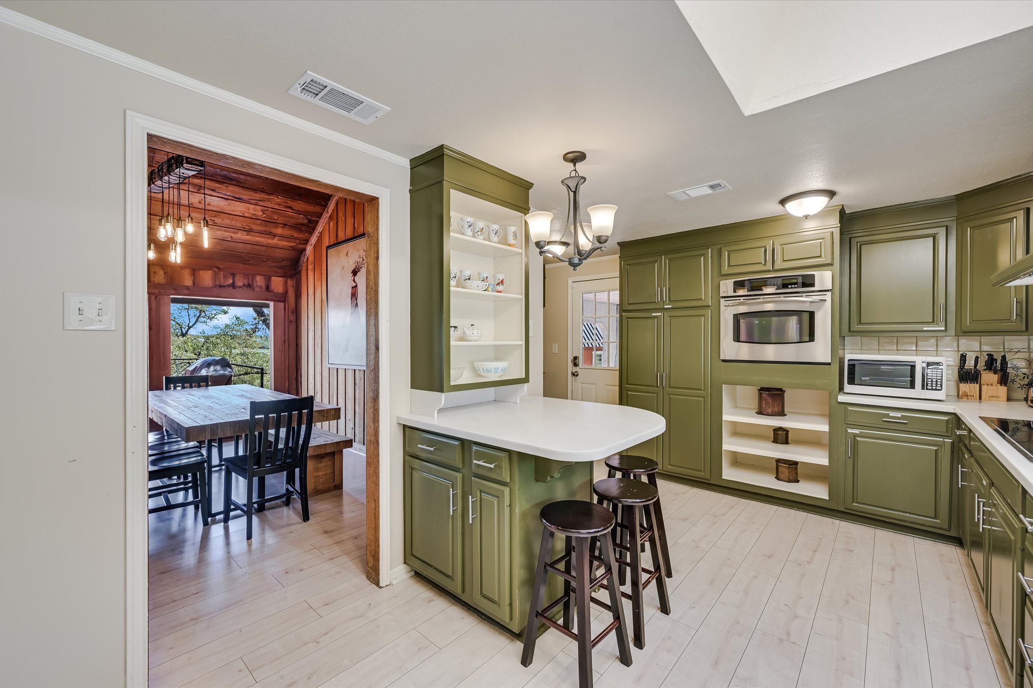 411 Whitetail Ridge Austin, TX 78737 - Photo 11 of 38 Kitchen featuring green cabinets, open shelves, hanging lights, a breakfast bar, and light countertops