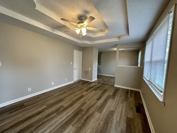 a view of an empty room and chandelier fan