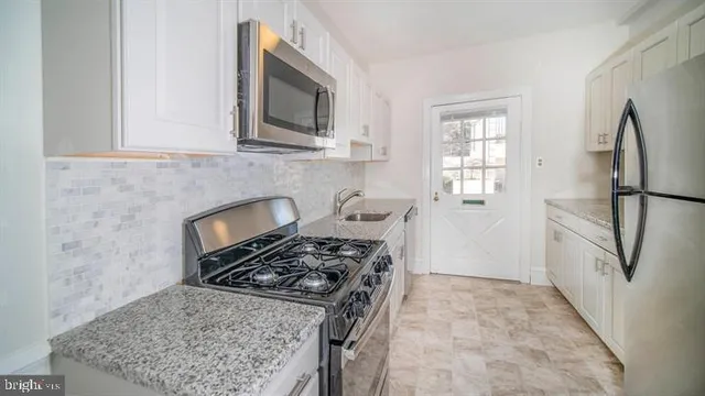 a kitchen with stainless steel appliances granite countertop a stove a refrigerator and a microwave