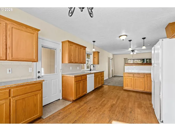 a large kitchen with stainless steel appliances kitchen island granite countertop a stove a sink dishwasher and white cabinets with wooden floor