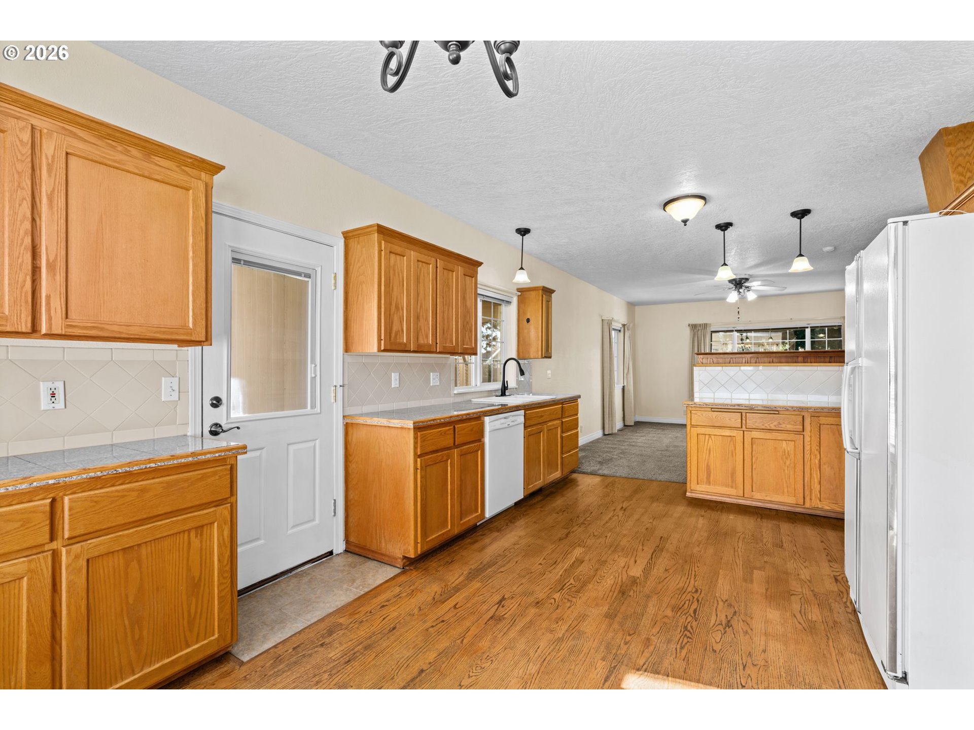 6540 B Street Springfield, OR 97478 - Photo 12 of 48 a large kitchen with stainless steel appliances kitchen island granite countertop a stove a sink dishwasher and white cabinets with wooden floor