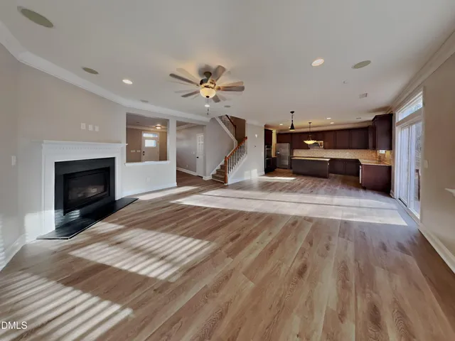 a view of a livingroom with a fireplace a ceiling fan and wooden floor