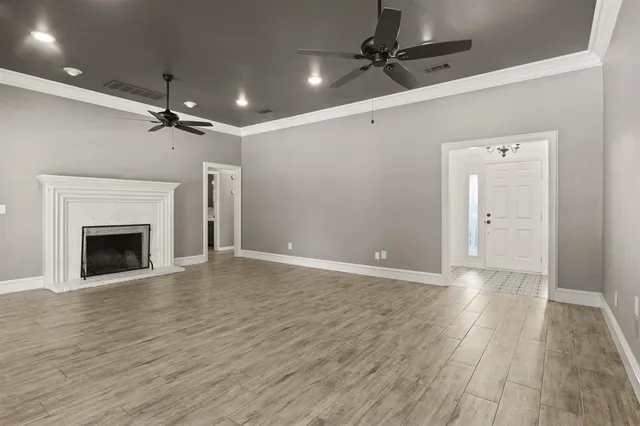 a view of empty room with wooden floor ceiling fan and fireplace