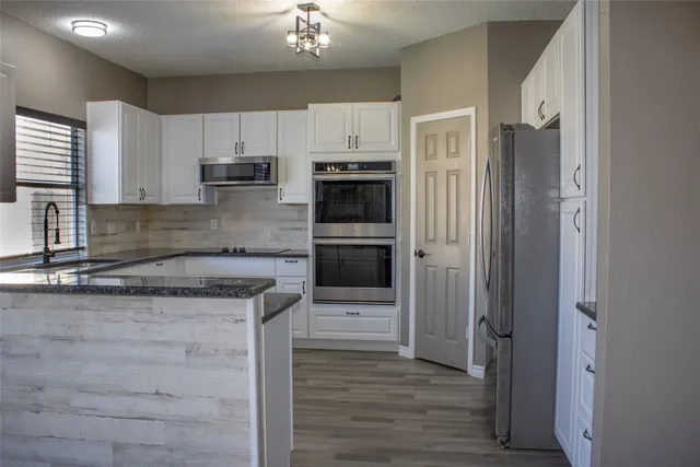 a kitchen with stainless steel appliances granite countertop a refrigerator and a stove top oven