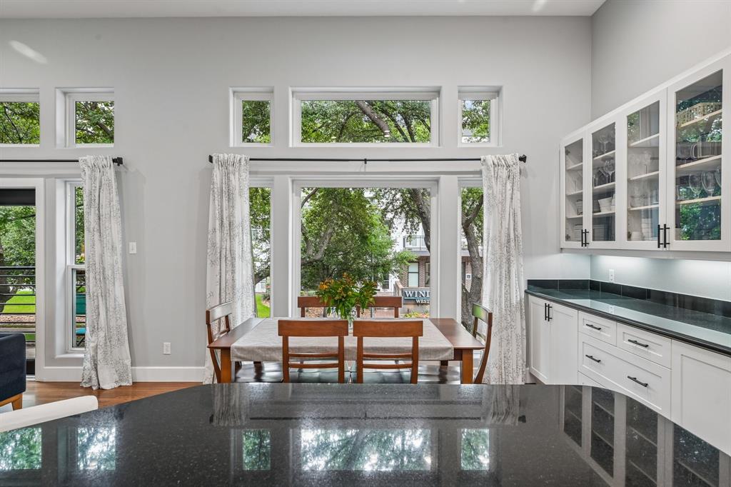 3553 Wheeler Street Dallas, TX 75209 - Photo 12 of 35 Dining space viewed from kitchen island with floor-to-ceiling windows, treetop views, and glass-front cabinetry