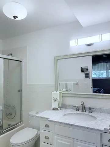 a bathroom with a granite countertop toilet sink and a mirror