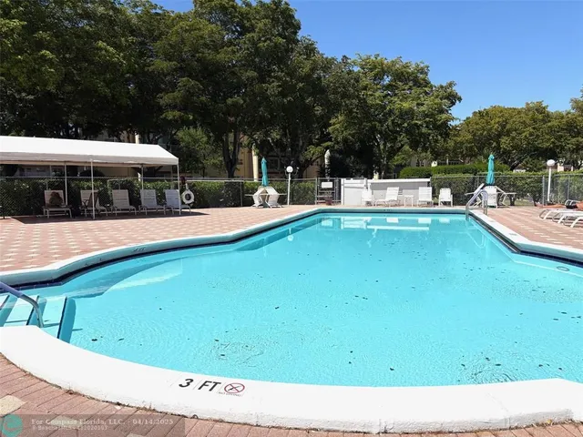 a view of a swimming pool with a lawn chairs under an umbrella