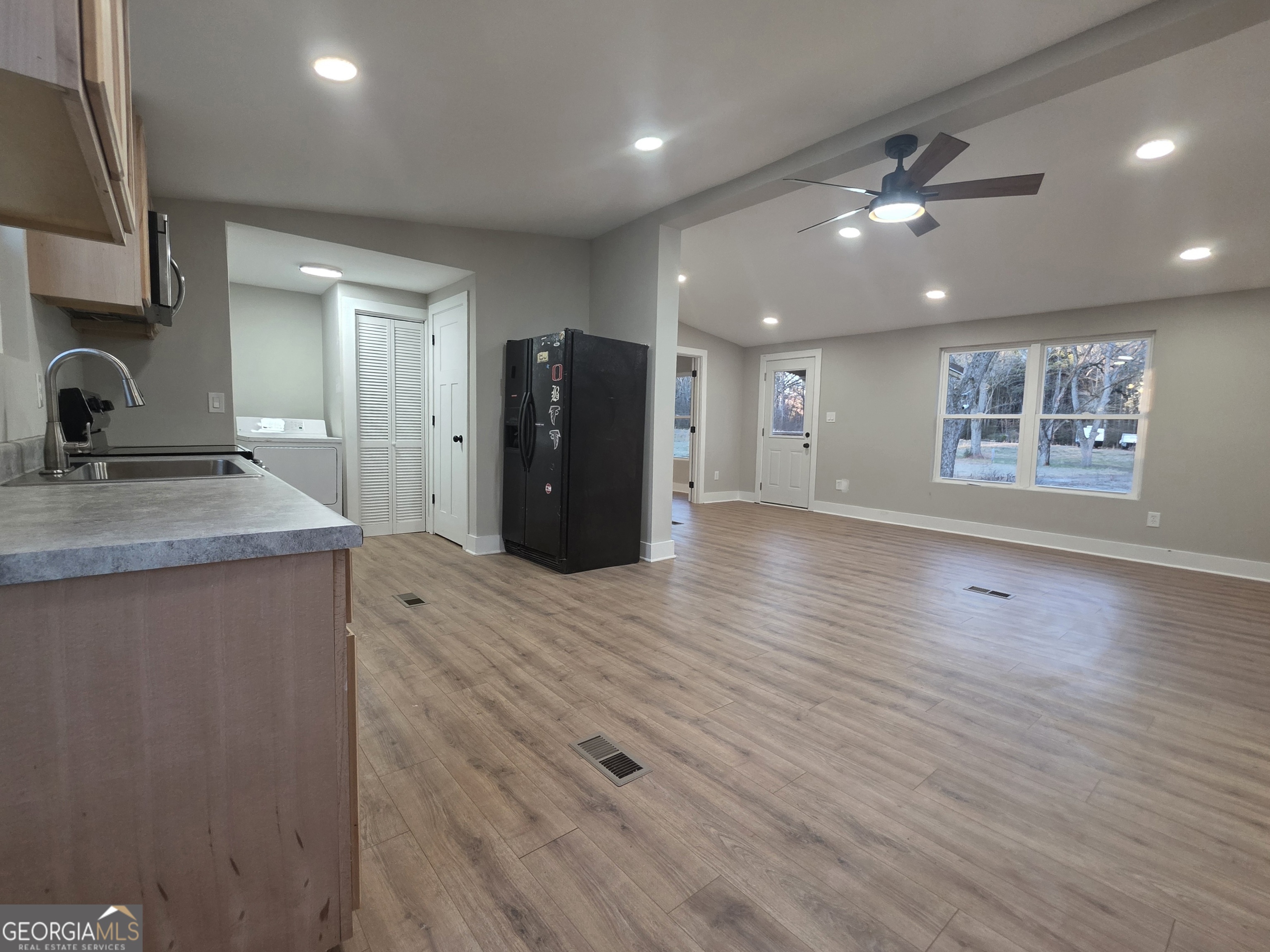 115 Little Street Williamson, GA 30292 - Photo 4 of 9 an empty room with wooden floor and a kitchen