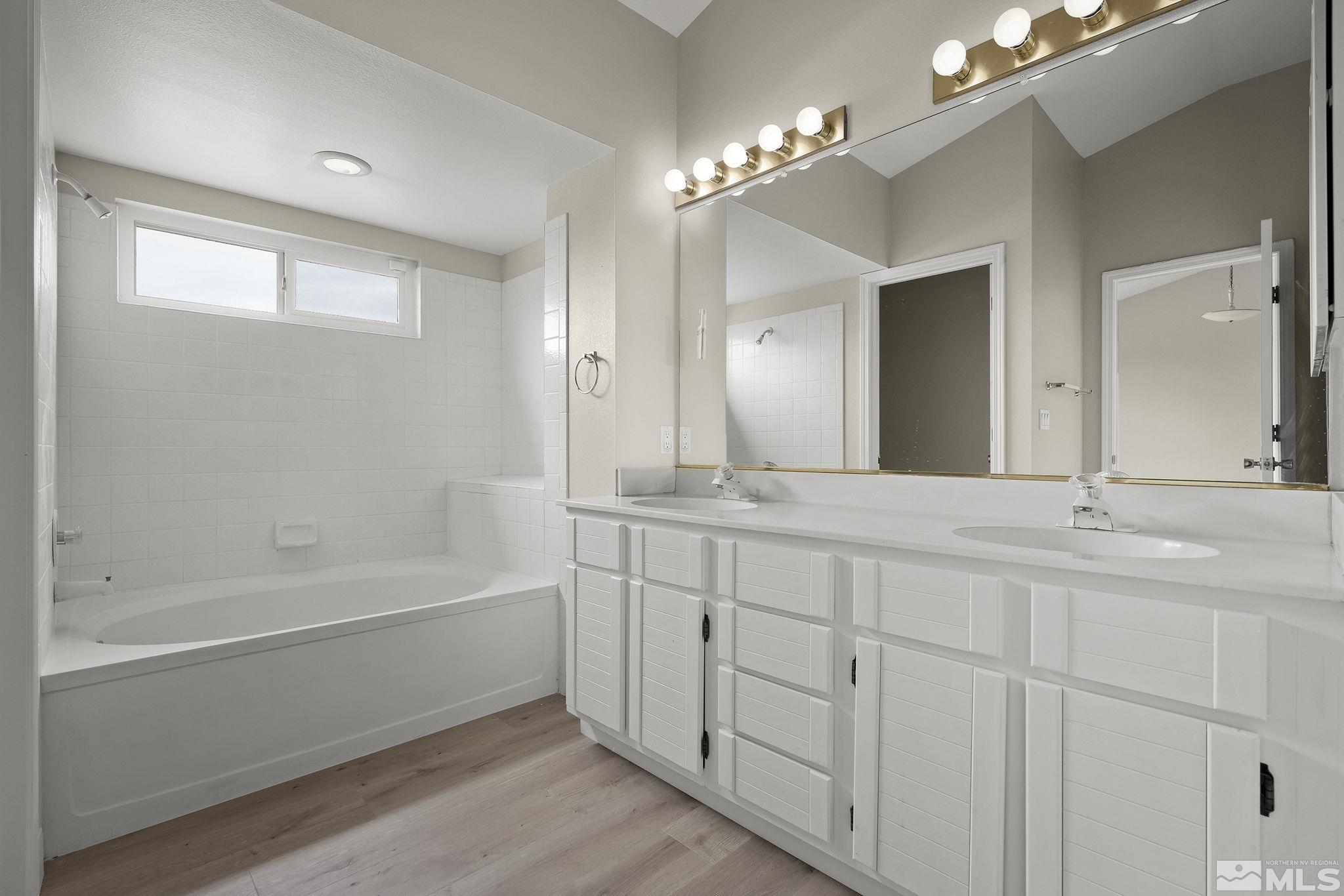 5267 Simons Drive Reno, NV 89523 - Photo 19 of 33 a bathroom with a tub a double vanity sink and a large mirror