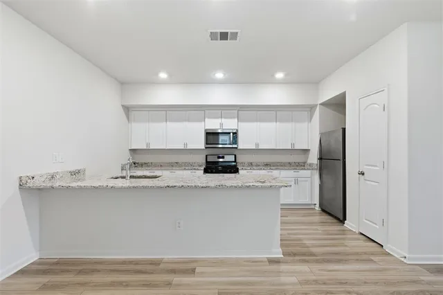 a large kitchen with stainless steel appliances granite countertop a stove a sink and a refrigerator