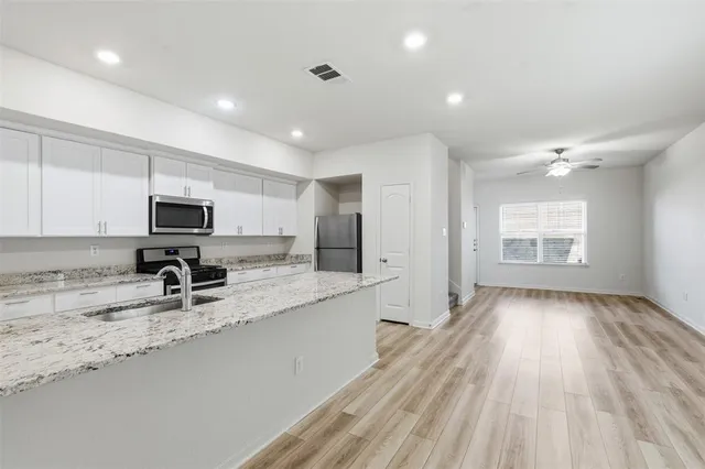 a kitchen with granite countertop a sink stainless steel appliances and cabinets