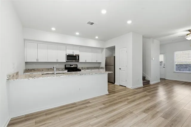 a kitchen with stainless steel appliances granite countertop a refrigerator and a stove top oven