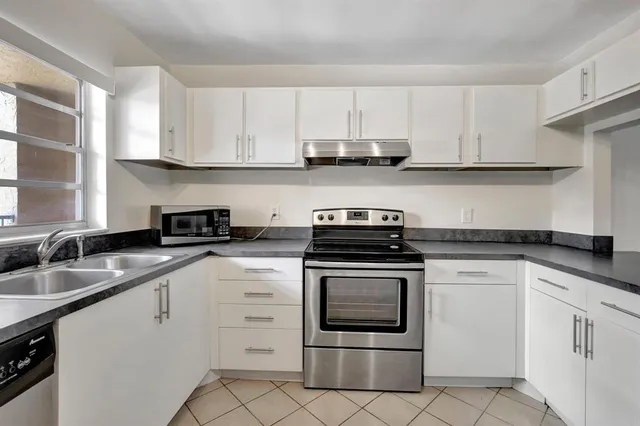 a kitchen with granite countertop white cabinets and white stainless steel appliances