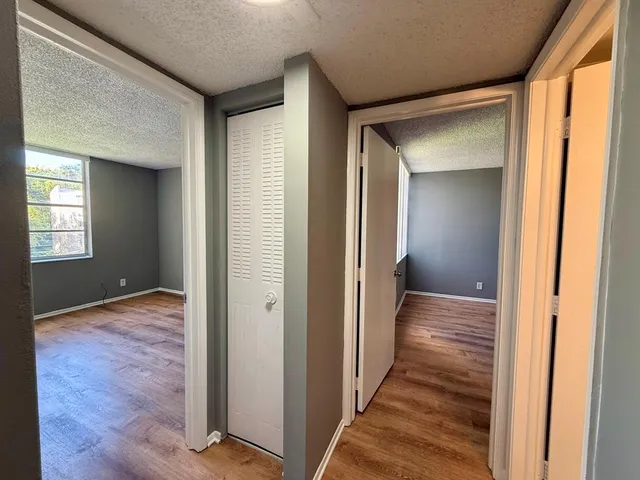 a view of a hallway with wooden floor and closet