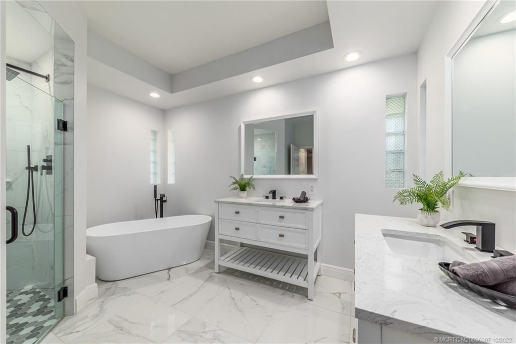5374 Southeast Horseshoe Point Road Stuart, FL 34997 - Photo 21 of 38 a spacious bathroom with a double vanity sink a mirror a bathtub and a shower