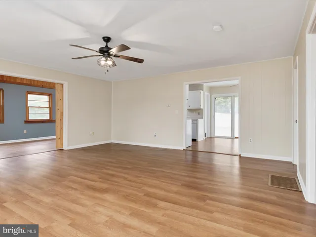 a view of empty room with wooden floor and fan