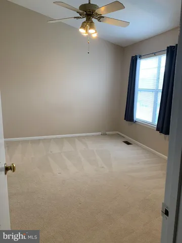 an empty room with a chandelier fan and windows