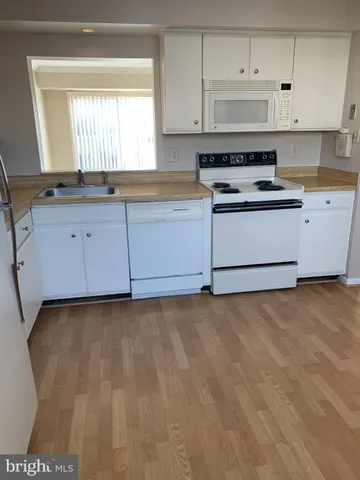 a kitchen with granite countertop white cabinets and white appliances
