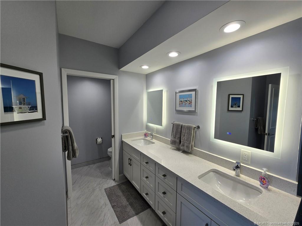 185 Northeast Edgewater Drive, Unit 5105 Stuart, FL 34996 - Photo 20 of 28 a bathroom with a double vanity sink and a mirror
