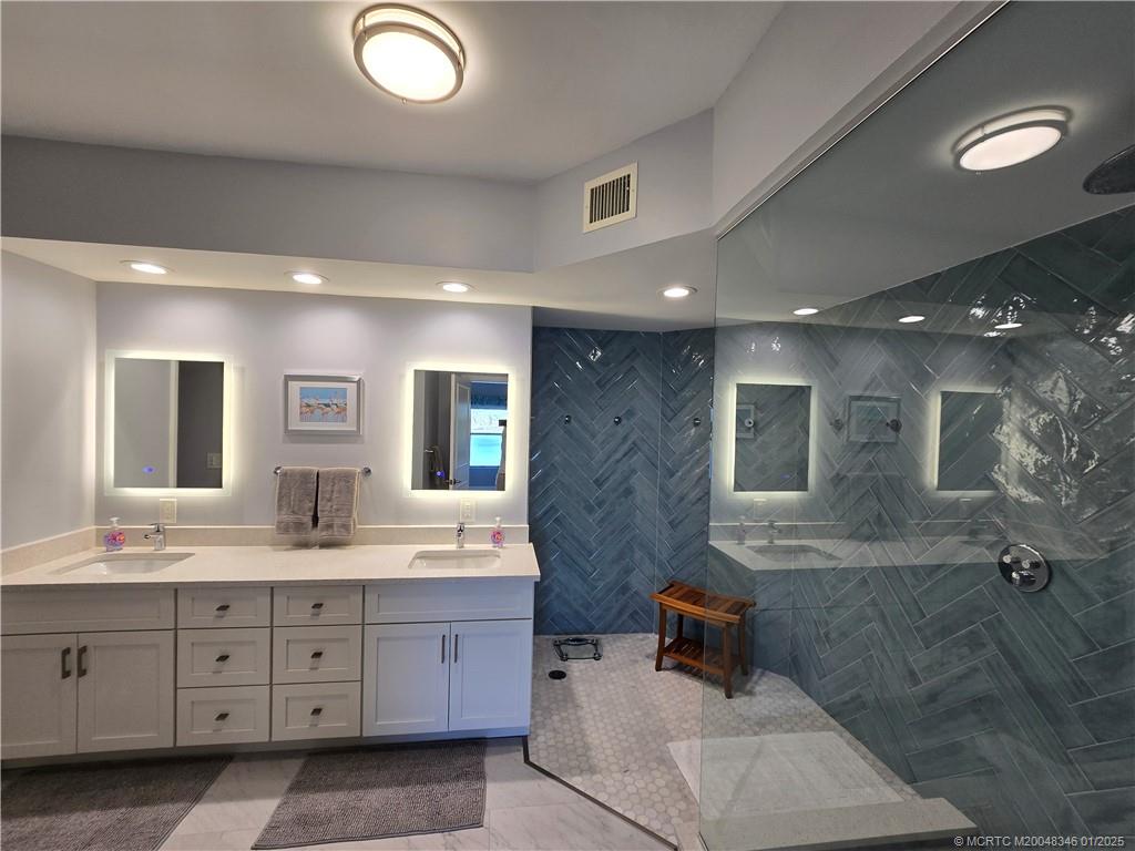185 Northeast Edgewater Drive, Unit 5105 Stuart, FL 34996 - Photo 21 of 28 a spacious bathroom with double vanity a sink a mirror and a shower