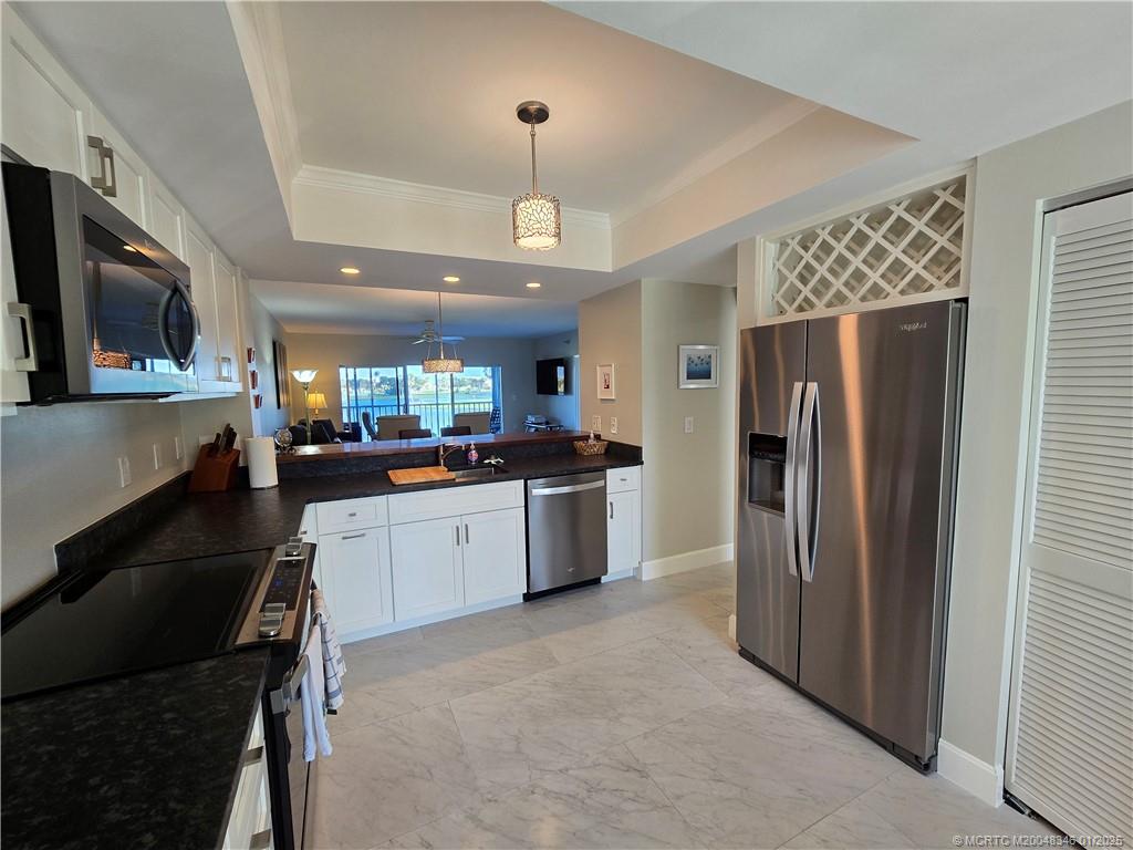 185 Northeast Edgewater Drive, Unit 5105 Stuart, FL 34996 - Photo 4 of 28 a white kitchen with a refrigerator a stove top oven a sink and cabinets