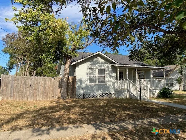 a view of a white house next to a yard with wooden fence