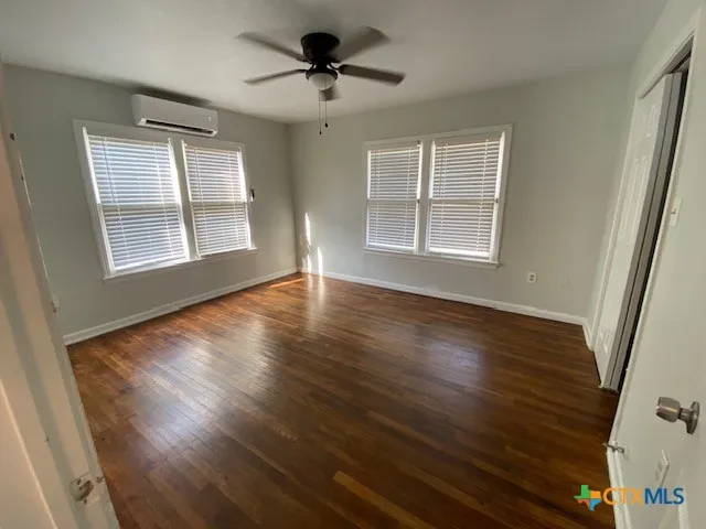 a view of an empty room with wooden floor and a window