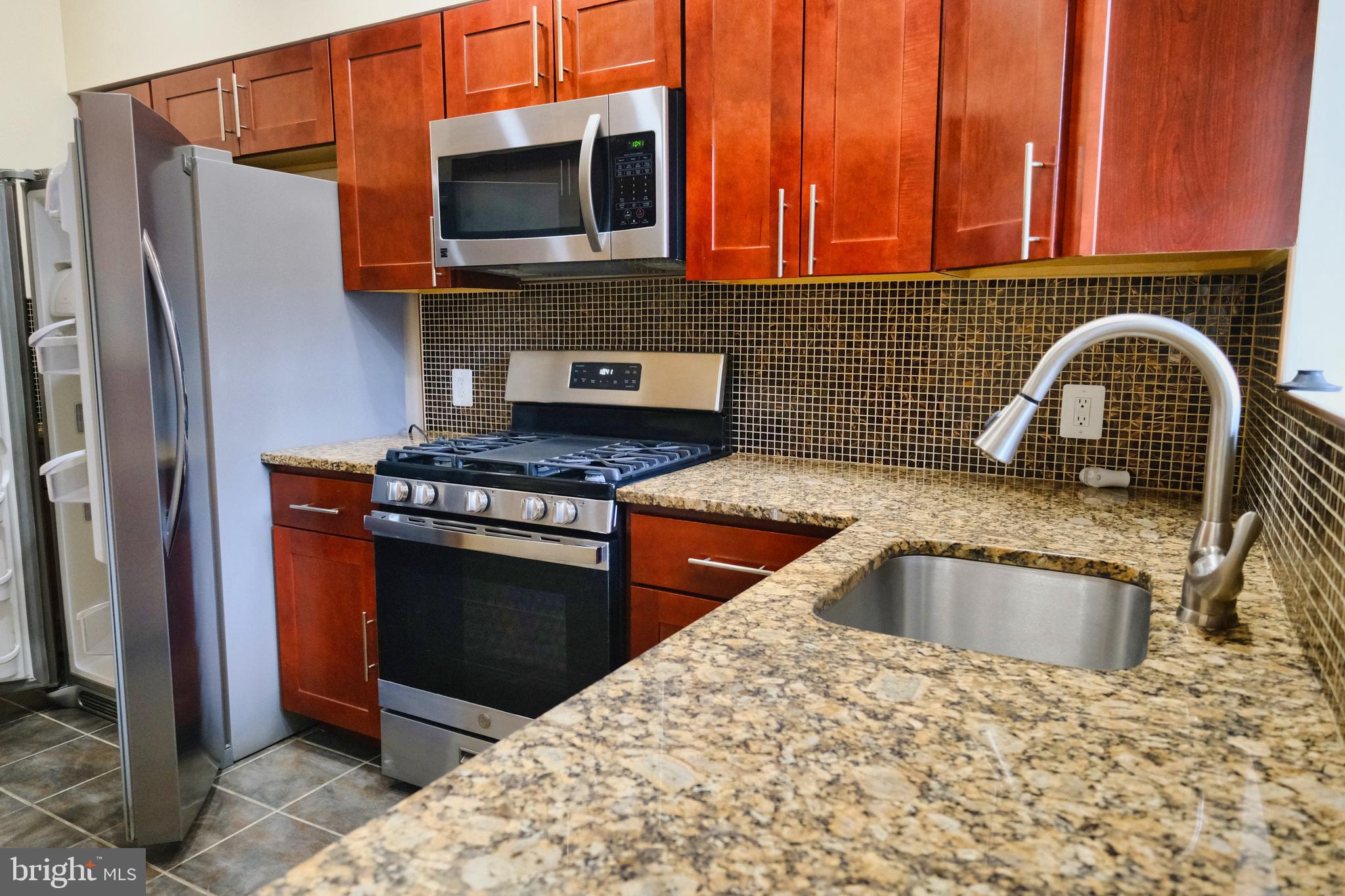 2225 Brookfield Avenue Baltimore, MD 21217 - Photo 19 of 28 a kitchen with stainless steel appliances granite countertop a stove a sink and a microwave