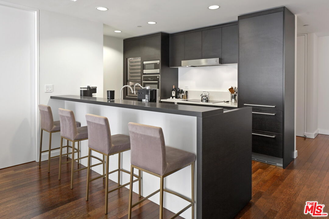 6250 Hollywood Boulevard, Unit 5J Los Angeles, CA 90028 - Photo 6 of 40 a kitchen with a table chairs refrigerator and microwave