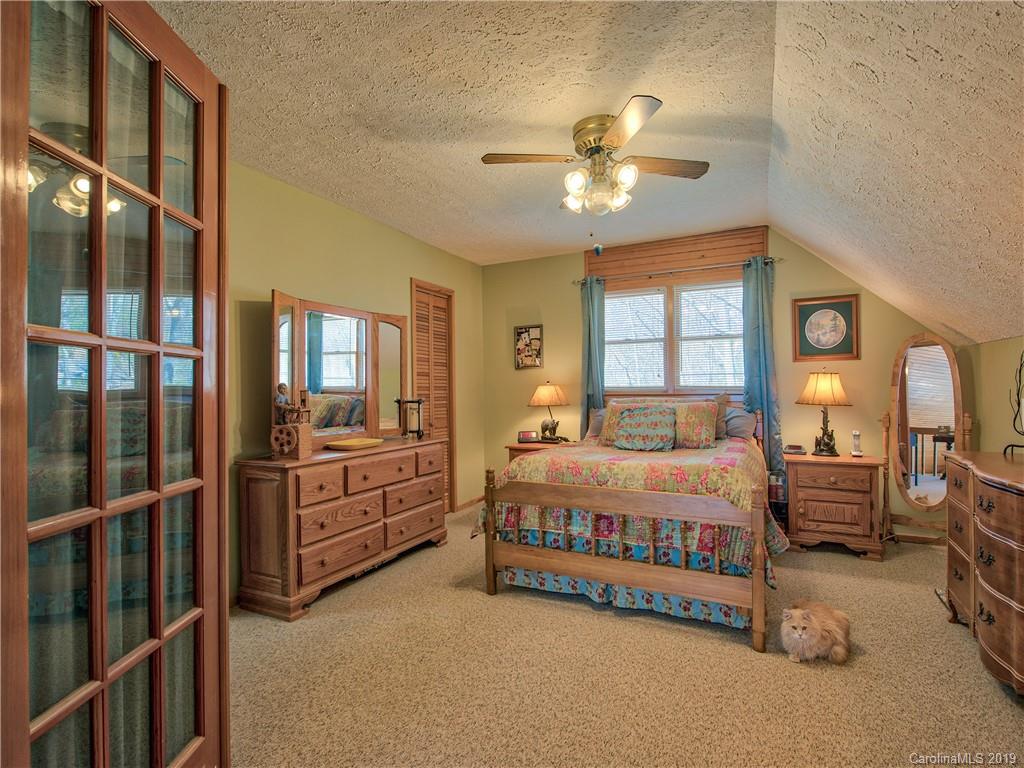 464 Bent Tree Road Maggie Valley, NC 28751 - Photo 11 of 38 a spacious bedroom with a bed table closet and flat screen tv