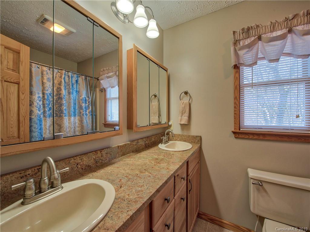 464 Bent Tree Road Maggie Valley, NC 28751 - Photo 12 of 38 a bathroom with a granite countertop sink a mirror and a shower