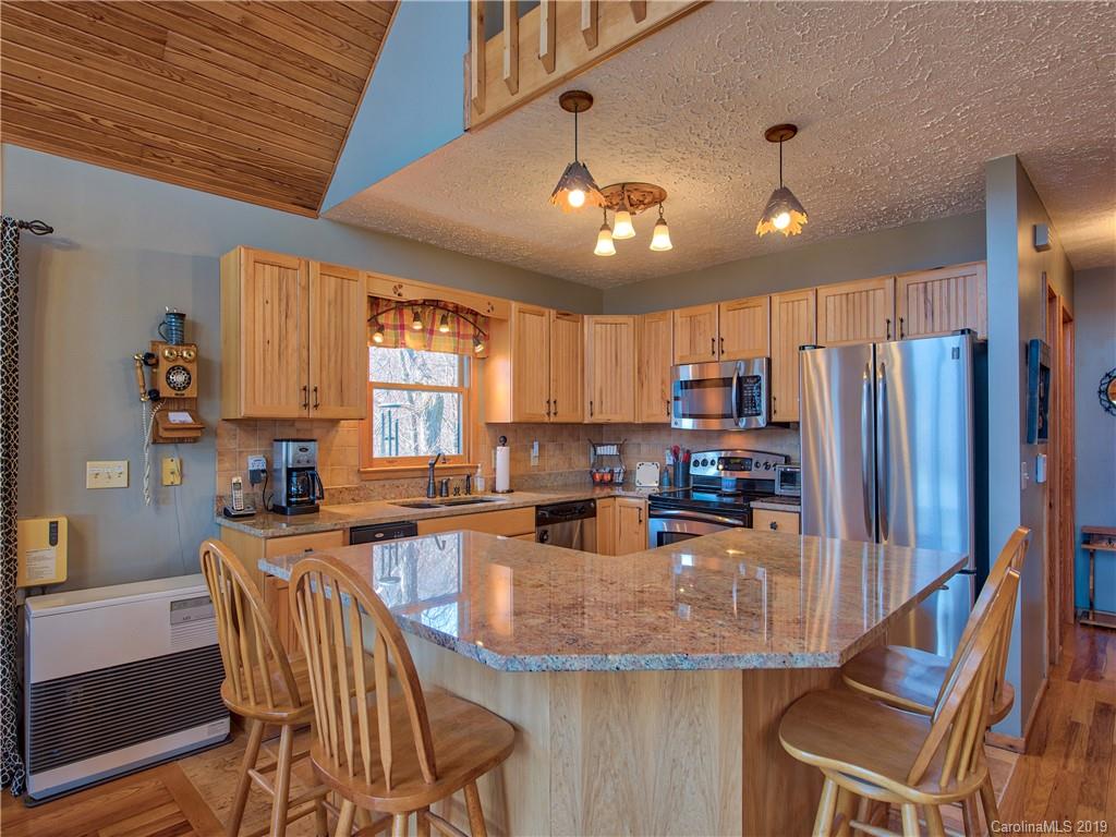 464 Bent Tree Road Maggie Valley, NC 28751 - Photo 7 of 38 a kitchen with stainless steel appliances granite countertop a stove top oven a refrigerator a sink and chairs